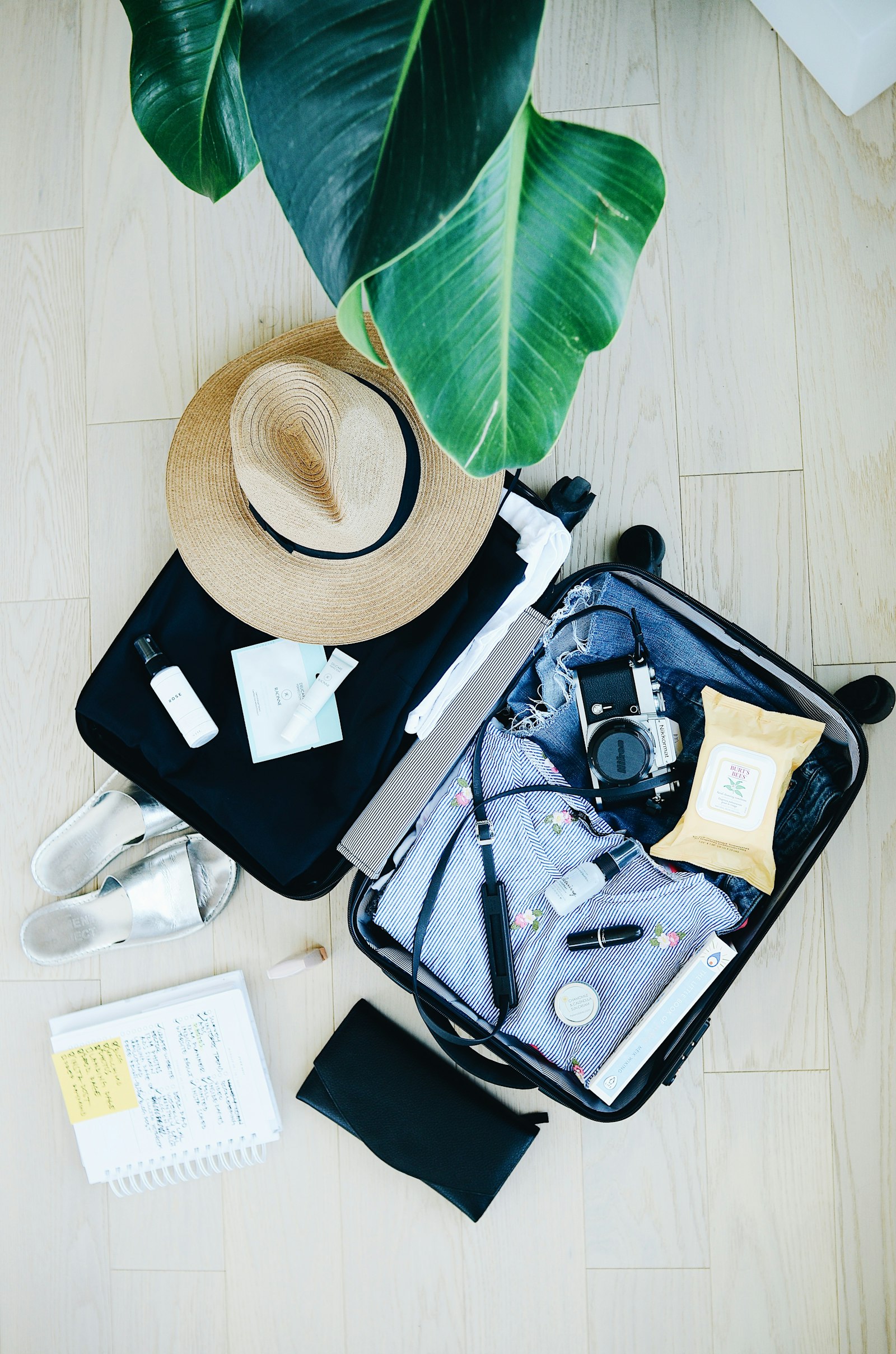 offener Koffer mit Reiseutensilien und Hut